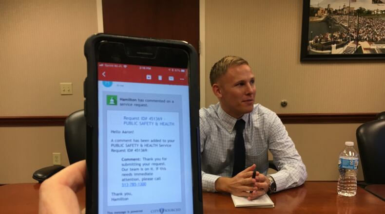 Hamilton city senior analyst Aaron Hufford describes the new 311 Hamilton App, while a phone shows a confirmation message that the app sends to someone who has sent a complaint, request for help, compliment or suggestion through the system, which goes online today. MIKE RUTLEDGE / STAFF