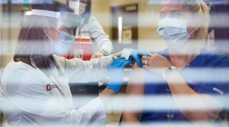 Pharmacist Emily Vrontos injects Andrea Yagodich, a respiratory therapist, with the Pfizer-BioNTech COVID-19 vaccine at The Ohio State University Wexner Medical Center in Columbus, Ohio, Tuesday, Dec. 15, 2020. Vaccines are rolling out to health workers now and will reach the arms of the rest of us by spring. (Brian Kaiser/The New York Times)