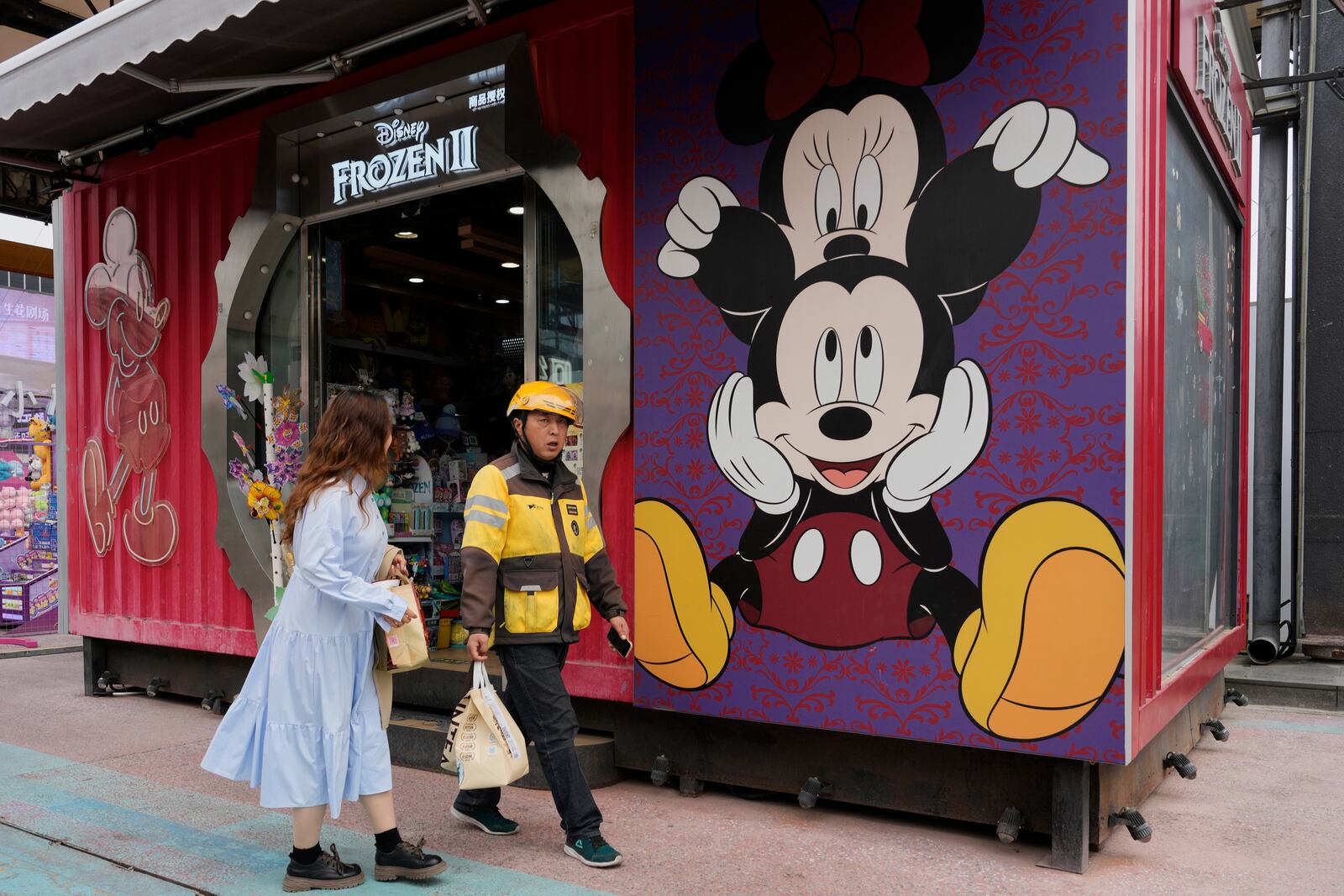 A delivery man past by a Disney store at a mall in Beijing, China, Tuesday, April 8, 2025. (AP Photo/Ng Han Guan)