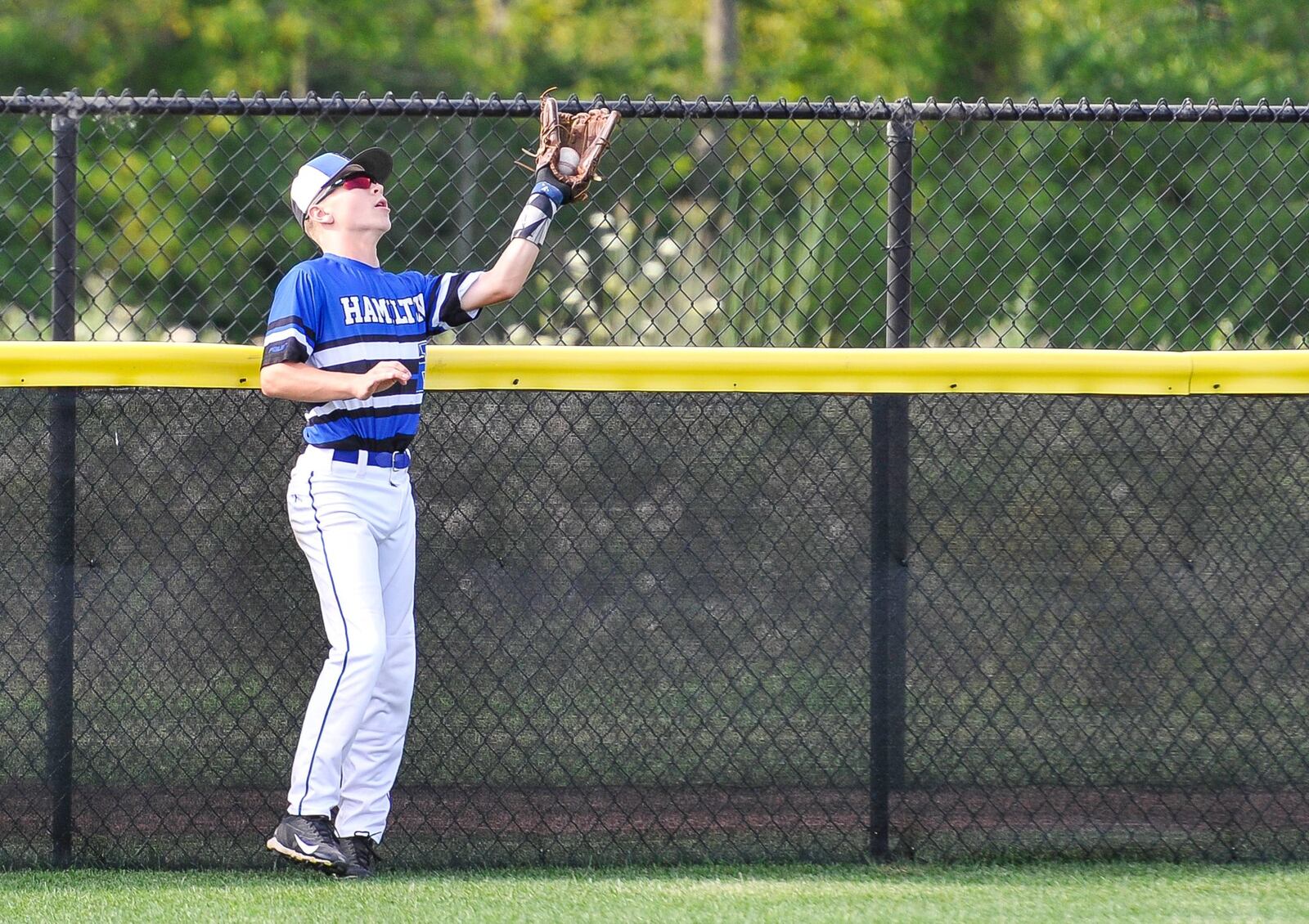 Hamilton West Side’s Lake Cundiff makes a catch at the fence for an out during their 11-3 loss to Grosse Pointe Woods-Shores (Mich.) in their Little League Great Lakes Regional game Friday at Grand Park Sports Campus in Westfield, Ind. NICK GRAHAM/STAFF