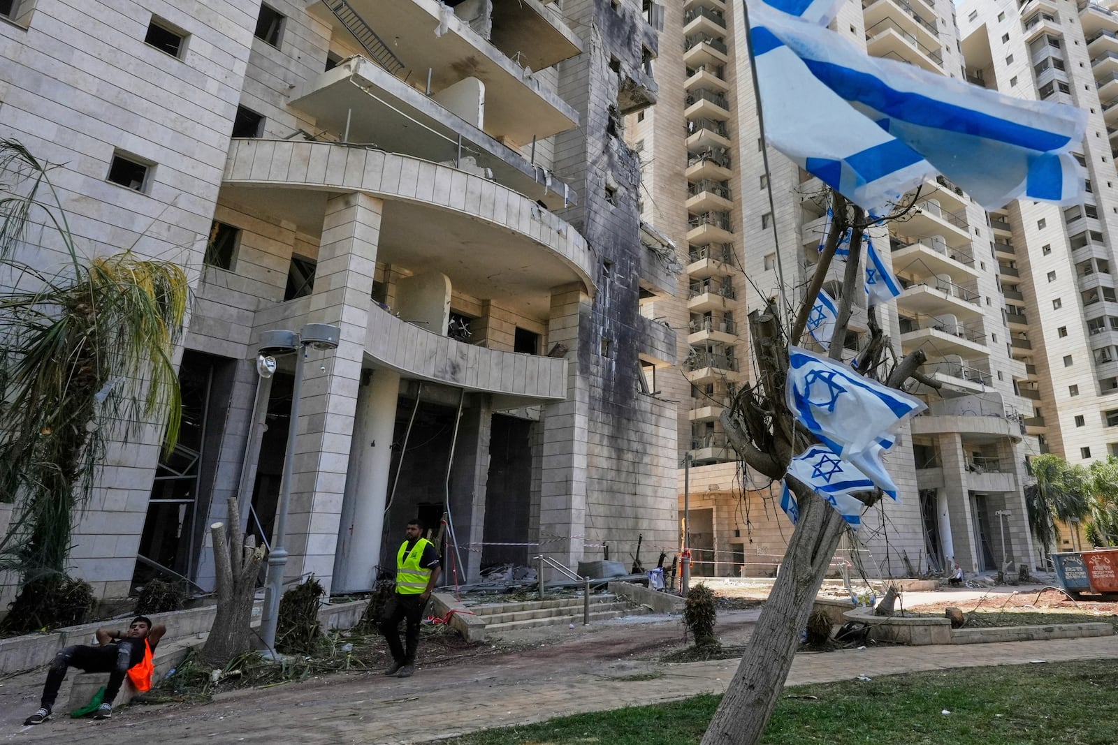 An Israeli security guard stands at the entrance of a residential building hit by a missile launched from Iran, in Petah Tikva, Israel, Monday, June 16, 2025. (AP Photo/Baz Ratner)