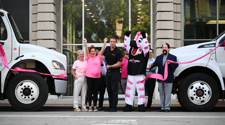 Drue Chrisman, a former Bengals punter and owner of the Pink Zebra Moving franchise in Lawrenceburg, Ind., expands into downtown Hamilton, Ohio. Pictured is the ribbon cutting in front of the Rentschler Building at the corner of High and Second streets. MICHAEL D. PITMAN/STAFF