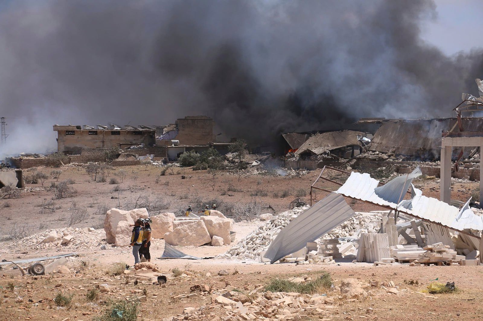 In this photo provided by the Syrian Civil Defense White Helmets, Syrian Civil Defense workers inspect the explosion side in Maarat Misrin village, in Idlib province, north Syria, Thursday, July, 24, 2025. (Syrian Civil Defense White Helmets via AP)