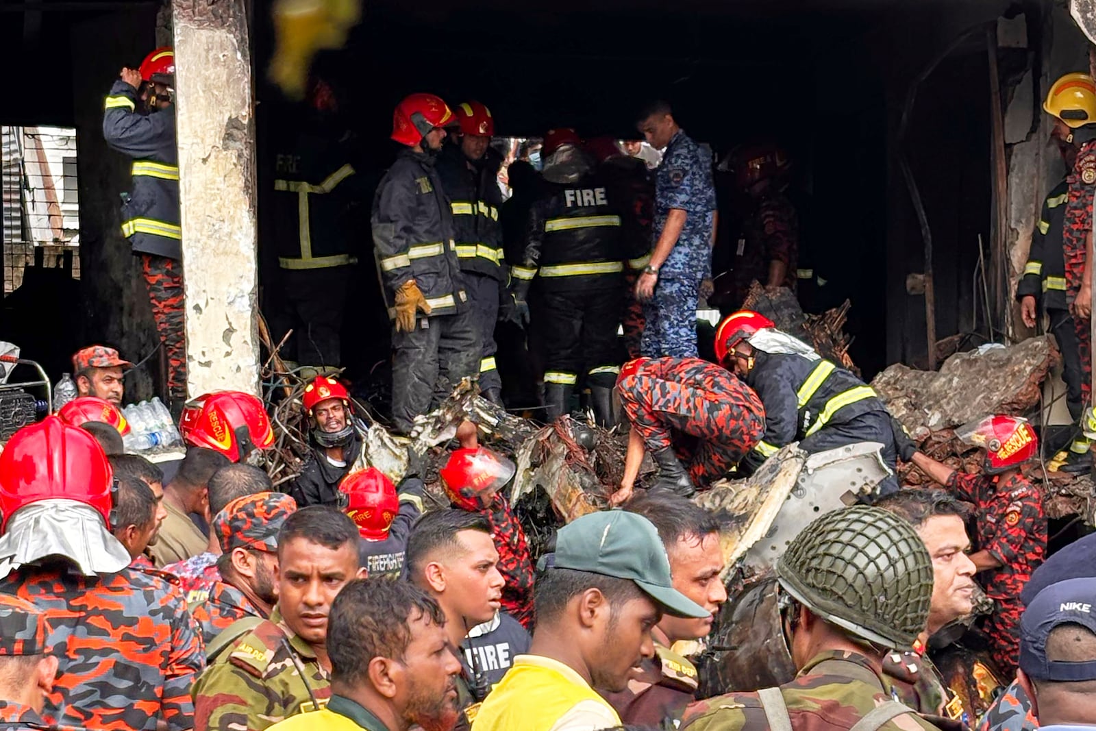 Firemen check the wreckage of a Bangladesh Air Force training aircraft that crashed onto a school campus in Dhaka, Bangladesh, Monday, July 21, 2025. (AP Photo/Al-emrun Garjon)