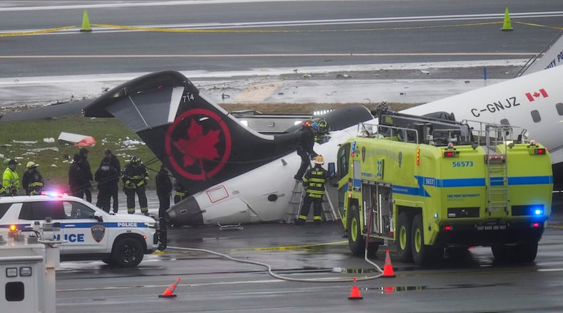 Firefighters and investigators examine the site, Monday, March 23, 2026, where an Air Canada jet came to rest after colliding with a Port Authority firetruck at LaGuardia Airport, after landing Sunday night in New York. (AP Photo/Seth Wenig)