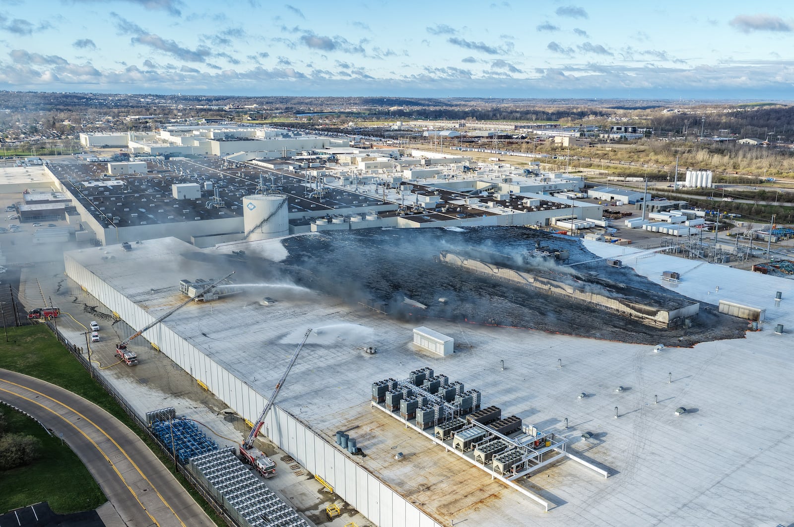 Morning crews work to extinguish remaining flames at the Fuyao Glass America plant in Moraine following a large fire. NICK GRAHAM / STAFF