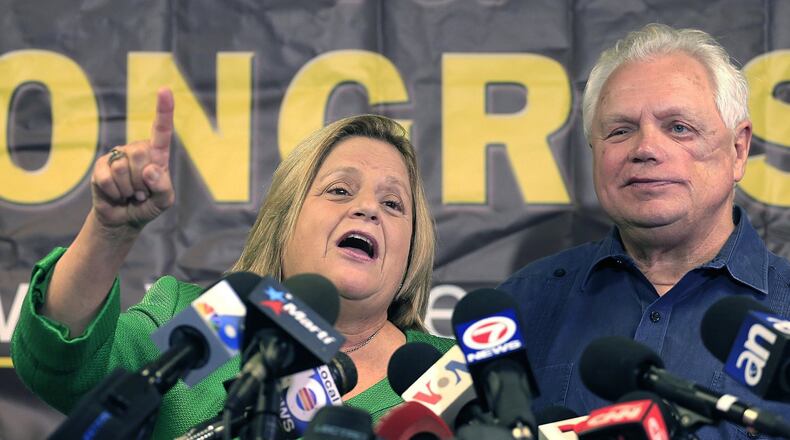 Ileana Ros-Lehtinen stands with her husband, Dexter Lehtinen, right, at the podium Monday, May 1, 2017, as she gives her final statement regarding her retirement from Congress. She says she is retiring at the end of her term next year. (Carl Juste/Miami Herald via AP)
