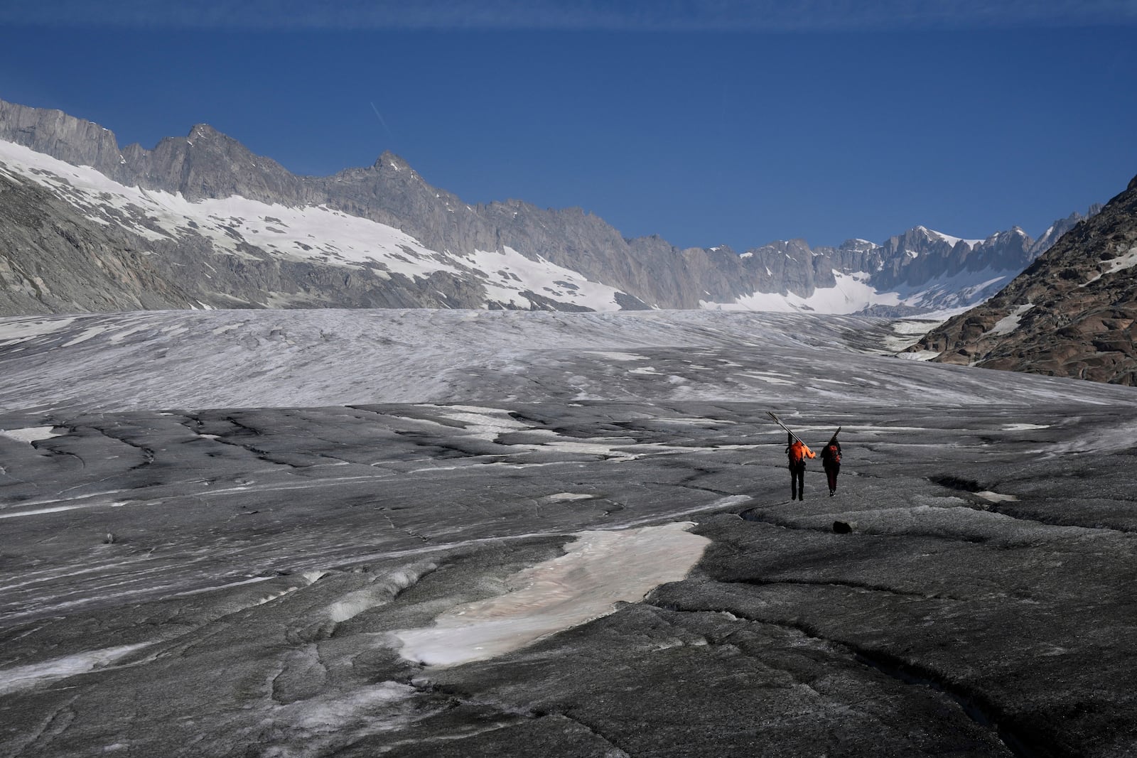 Matthias Huss, of the Federal Institute of Technology in Zurich and glacier monitoring group GLAMOS, and Monica Ursina Jaeger arrive at the Rhone glacier near Goms, Switzerland, June 10, 2025. (AP Photo/Matthias Schrader)