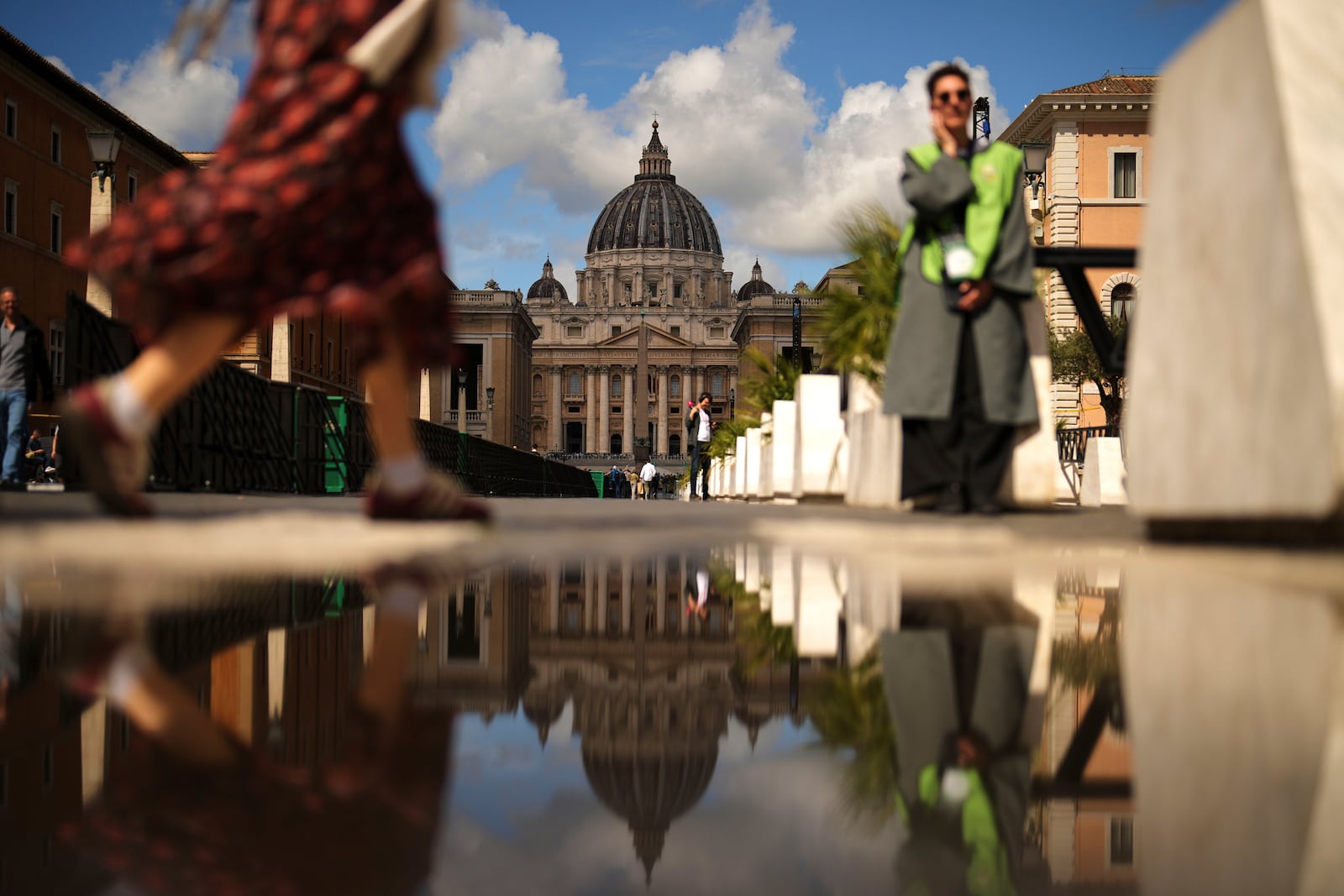 People walk near the St. Peter's Basilica, background, in Rome, on Tuesday, May 6, 2025, the day before of the upcoming conclave starting on May 7, to elect the 267th Roman pontiff. (AP Photo/Francisco Seco)