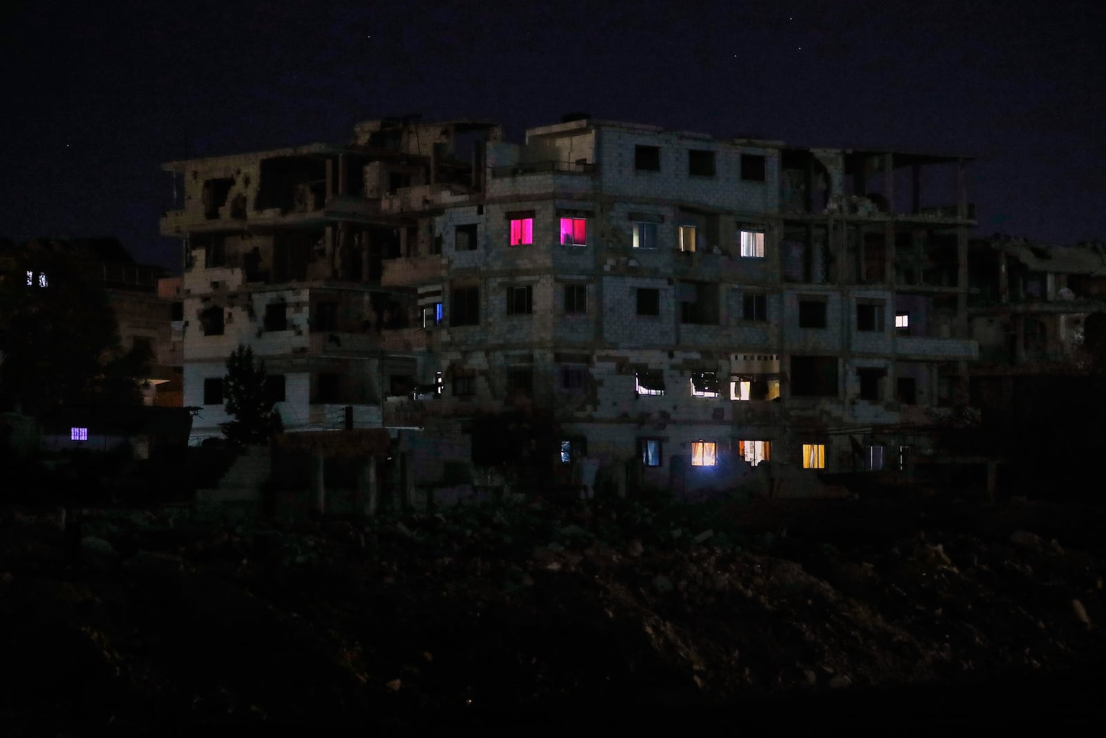 FILE - Lights illuminate a few windows of a damaged building in Damascus, Syria, early Thursday, March 27, 2025. (AP Photo/Omar Sanadiki, File)
