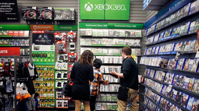 An employee assists customers shopping for Microsoft Xbox 360 video games inside a GameStop Corp. store in Louisville, Ky., on March 15, 2018. Bloomberg photo by Luke Sharrett.