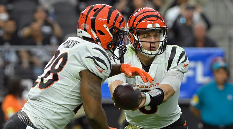 Cincinnati Bengals quarterback Joe Burrow (9) hands off the ball to running back Joe Mixon (28) during the first half of an NFL football game against the Las Vegas Raiders, Sunday, Nov. 21, 2021, in Las Vegas. (AP Photo/David Becker)