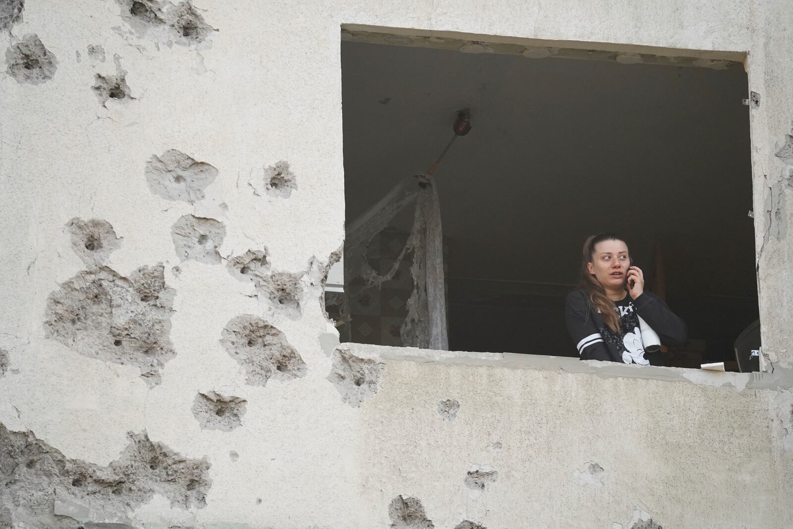 A woman looks though the window of her damaged apartment following a Russian strike in Kharkiv, Ukraine, Friday April 18, 2025. (AP Photo/Andrii Marienko)