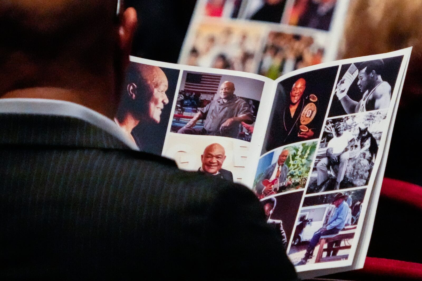 A mourner looks through photos in a program during a memorial service for Olympic and world champion boxer and minister George Foreman at Wortham Theater Center in Houston, Monday, April 14, 2025. (Brett Coomer/Houston Chronicle via AP)