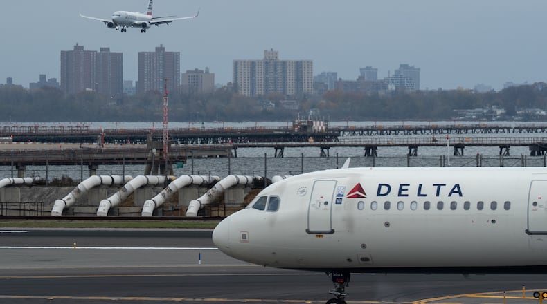 An American Airlines flight lands as a Delta Air Lines plane taxis at LaGuardia Airport (LGA) in the Queens borough of New York, Sunday, Nov. 9, 2025. (AP Photo/Adam Gray)