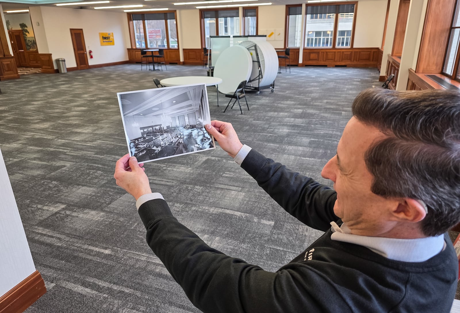 Douglas Berlon shows an old photograph of the second floor community room space. First Financial Bank is renovating its historic 300 High St. building in Hamilton, including preserving rare French wallpaper discovered during the project. The updated space will also feature a new public Community Room and a history wall highlighting the bank’s legacy. NICK GRAHAM/STAFF