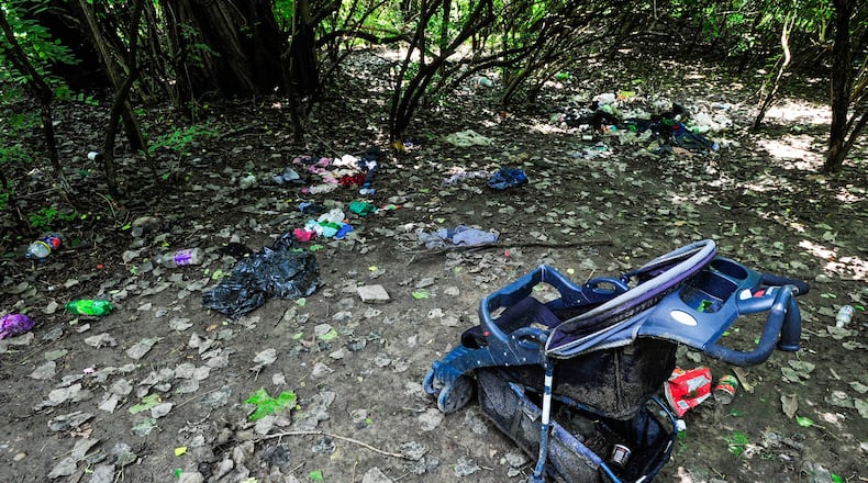 Clothes are strewn among a stroller and empty food containers in the woods at James G. Combs Park Friday, July 14 in Hamilton. NICK GRAHAM/STAFF