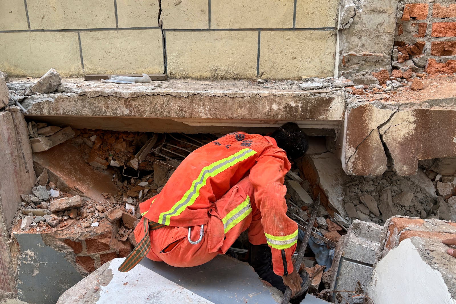 A firefighter recovers the belongings of victims from damaged buildings that house Governments' servants in Naypyitaw, Myanmar, Monday, April 28, 2025, one month after the earthquake. (AP Photo/Aung Shine Oo)