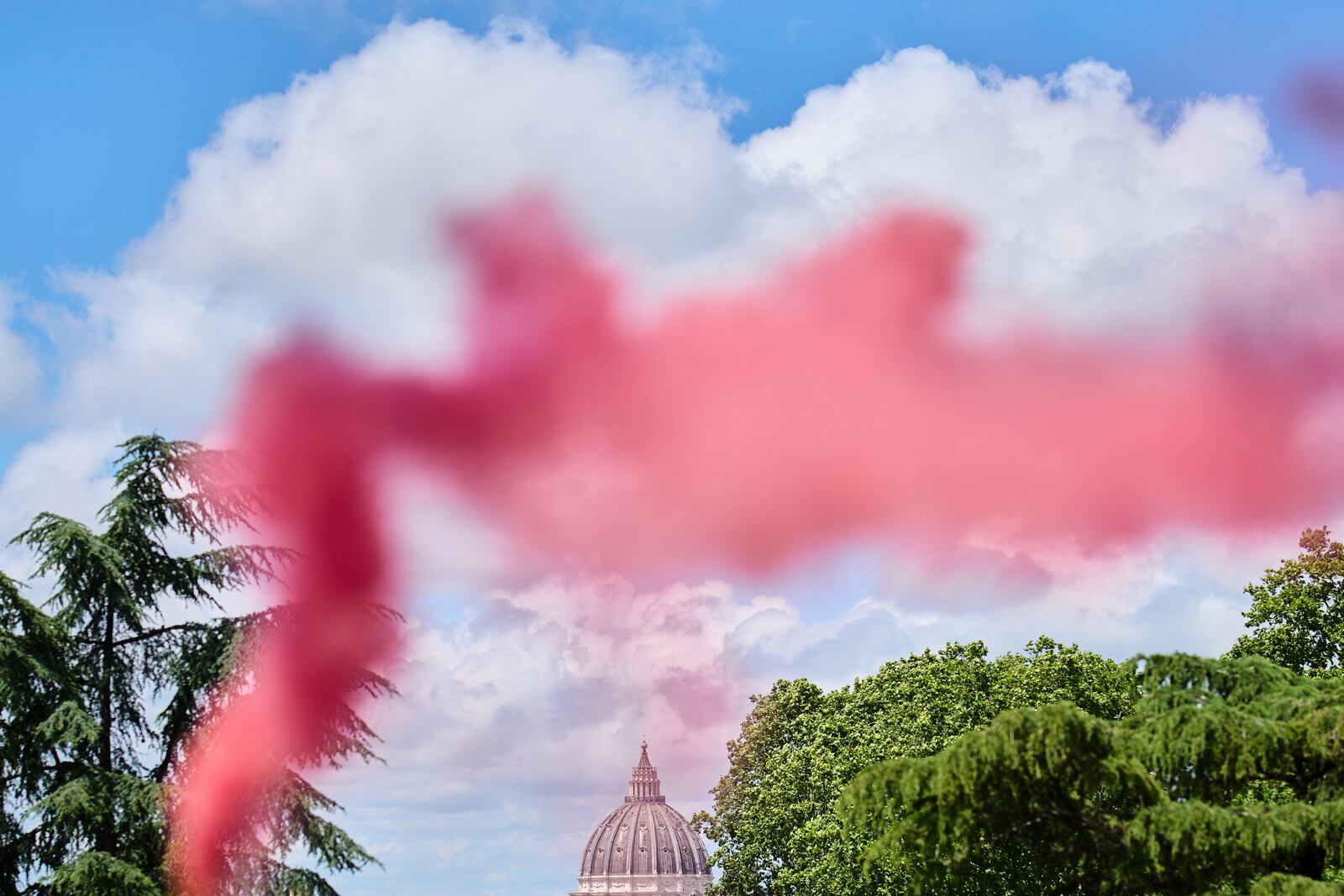 Pink smoke rises in front of St. Peter's Dome during a protest by the Women's Ordination Conference, calling for full equality for women in the Catholic Church on the first day of the conclave to elect the 267th pope, in Rome, Wednesday, May 7, 2025. (AP Photo/Bernat Armangue)