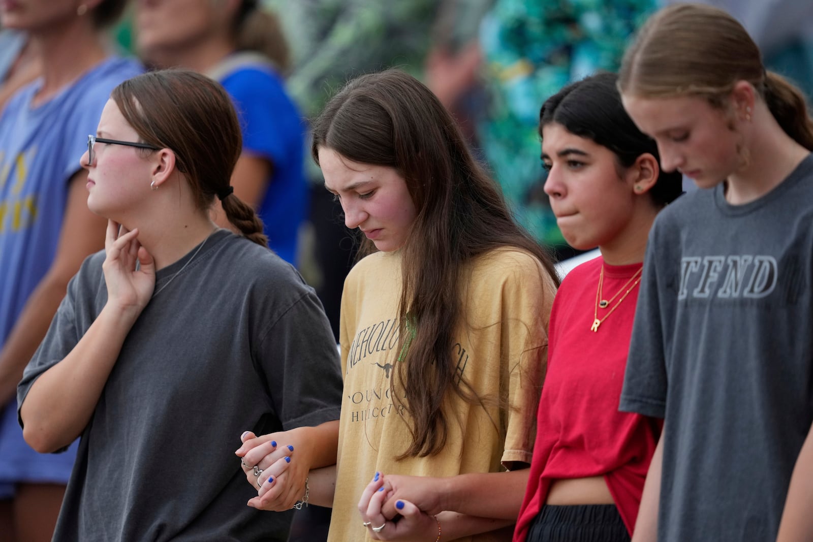 Attendees hold hands during a vigil for flooding victims at Tivy Antler Stadium on Wednesday, July 9, 2025, in Kerrville, Texas. (AP Photo/Ashley Landis)