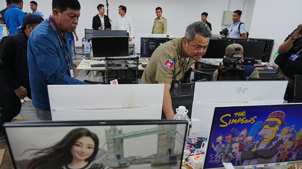 Bun Sosekha, Deputy Commissioner in charge of Security Unit, Phnom Penh Municipal Police, checks equipment confiscated in a raid by Cambodian police at a scam center in Phnom Penh, Cambodia, Wednesday, March 11, 2026. (AP Photo/Heng Sinith)