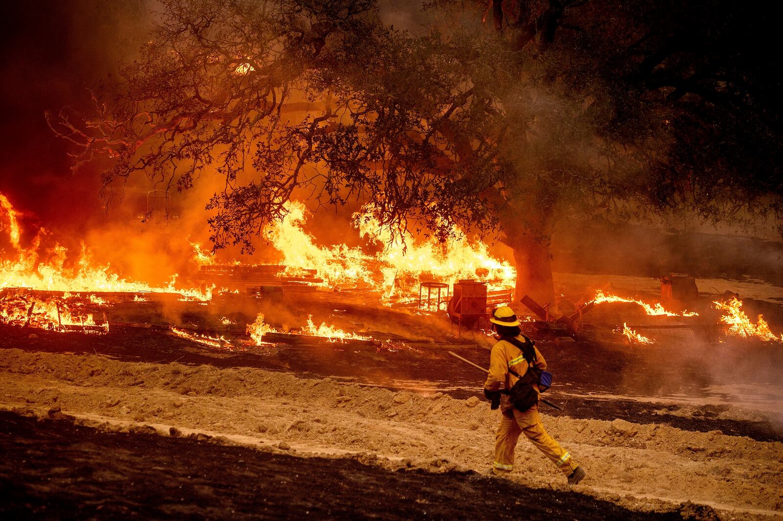 FILE - A firefighter passes flames while battling the Glass Fire in a Calistoga, Calif., vineyard Oct. 1, 2020. (AP Photo/Noah Berger, File)