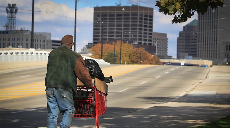 A pedestrian pushes a shopping cart with belongings across the Fourth Street bridge towards the Dayton skyline in 2013. The national poverty rate in 2016 was the lowest since before the recession according to new U.S. Census data. JIM WITMER / STAFF