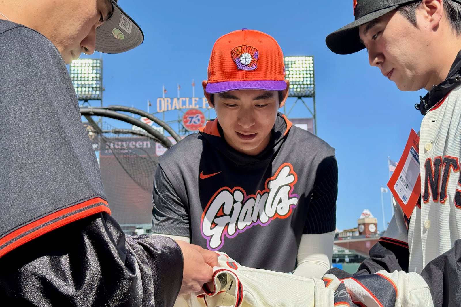 San Francisco Giants' Jung Hoo Lee, middle, signs autographs for fans before a baseball game between the Giants and the Arizona Diamondbacks in San Francisco, Tuesday, May 13, 2025. (AP Photo/Haven Daley)