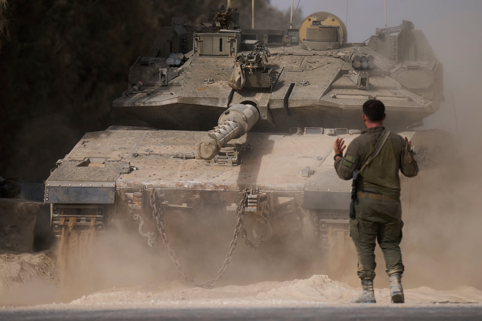 An Israeli soldier directs a tank at a staging area near the border with the Gaza Strip, in southern Israel, Tuesday, July 1, 2025. (AP Photo/Ariel Schalit)