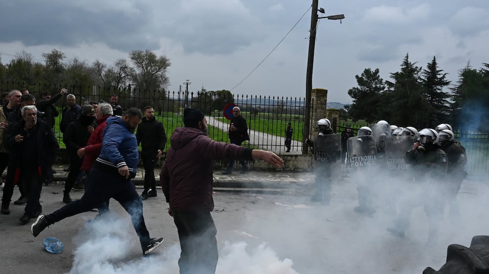 A man kicks a tear gas canister back toward riot police during clashes after farmers tried to block the main access road to Thessaloniki's international airport, northern Greece, on Friday, Dec. 5, 2025, as protests over delays in European Union-backed agricultural subsidy payments escalated. (AP Photo/Giannis Papanikos)