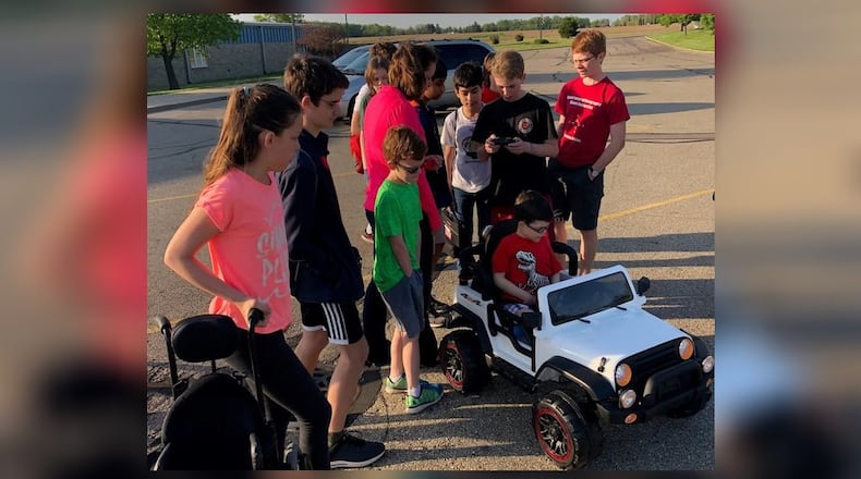 Kyle Robertson received his car in May and adjusted to it while his mother, Pamela Ollish, was being shown how to use the emergency stop switch by members of the geometry class which built it for him. CONTRIBUTED
