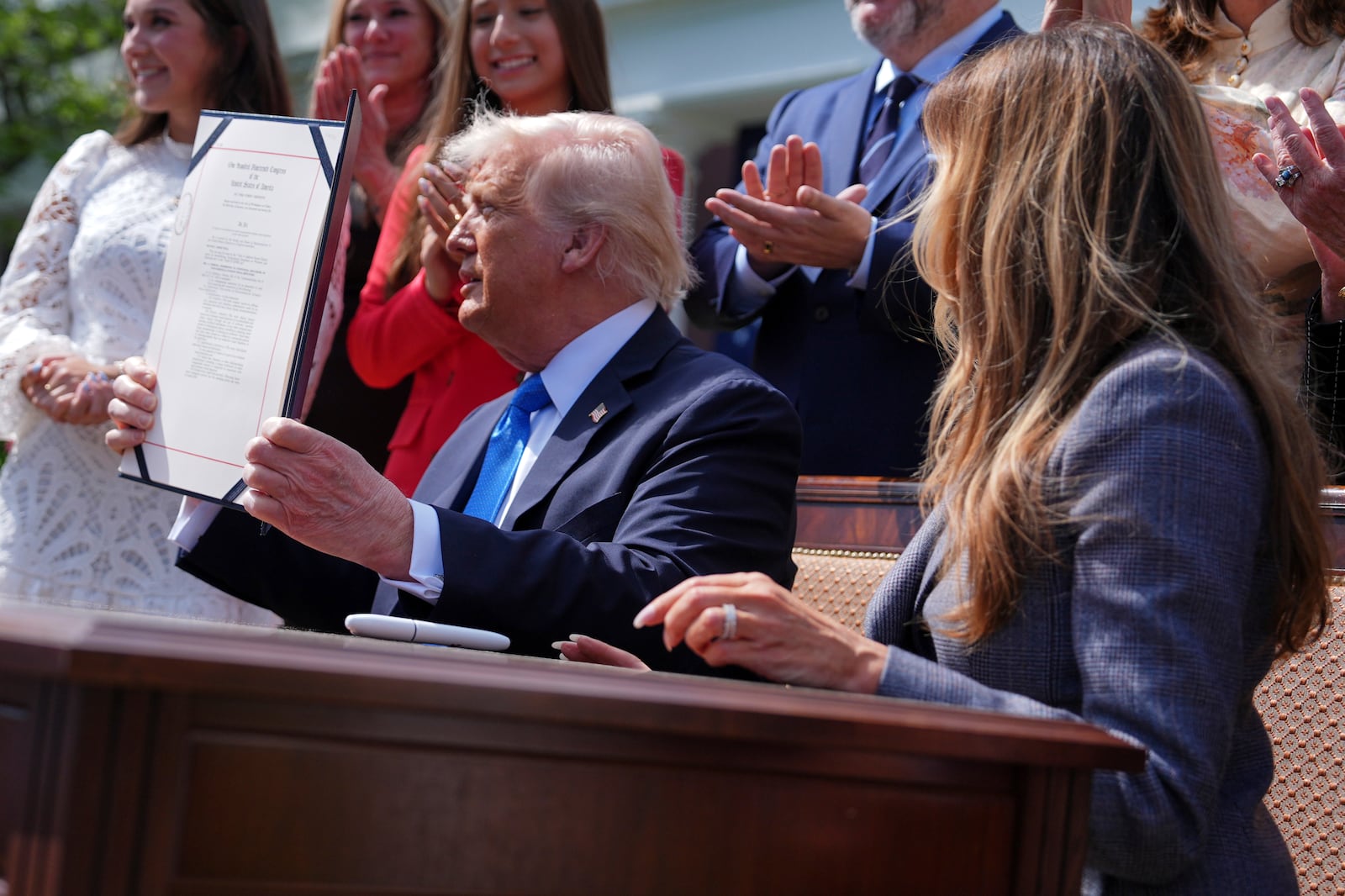 President Donald Trump holds up a bill for the "Take it Down Act" that he and first lady Melania Trump, right, signed in the Rose Garden of the White House, Monday, May 19, 2025, in Washington. (AP Photo/Evan Vucci)