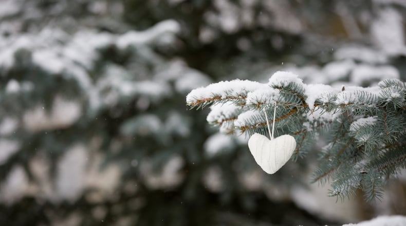 Closeup of knitted heart Christmas decoration on a Christmas tree with snow outdoors. Celebration, winter and holidays concept