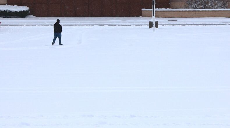 A man walks through a snow covered parking lot in Huber Heights Sunday morning. BILL LACKEY/STAFF (edited)