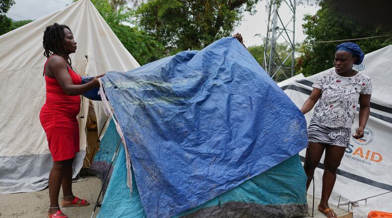 People place plastic tarps over their tents ahead of expected rain at a shelter for families displaced by gang violence in Port-au-Prince, Haiti, Thursday, Oct. 23, 2025. (AP Photo/Odelyn Joseph)