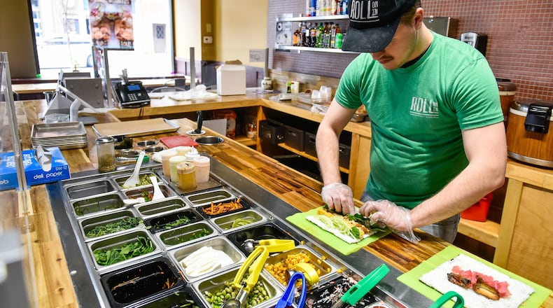 Zach Scheyer prepares a lunch entree Friday, April 5, 2019, at Roll On In Sushi Burritos & Bowls at 102 Main St. in Hamilton. The fast casual chain opened a new location July 14 in Warren County’s Hamilton Twp. and plans to introduce a Buzzed Bull Creamery into both locations later this year. NICK GRAHAM/STAFF