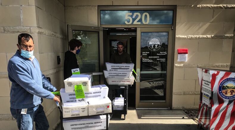 Brian Sleeth, left, Warren County Board of Elections director, wheels part of the county's more than 47,000 absentee ballots out the door. Workers on Monday took the ballots to a postal facility to be mailed Tuesday. In addition to voting absentee beginning Tuesday, registered voters can cast ballots by in-person early voting. Across Ohio, the hours this week through Friday are from 8 a.m. to 5 p.m. Twice as many Ohioans are expected to vote by mail than in 2016 because of the coronavirus pandemic. JIM NOELKER / STAFF