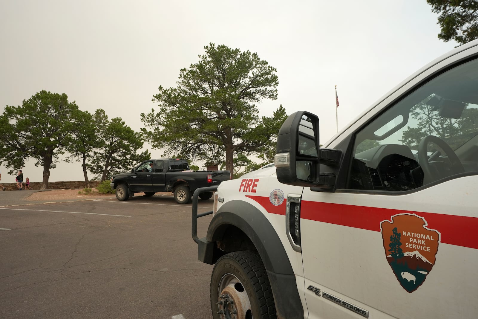 Smoke from the Dragon Bravo Fire moves over the Grand Canyon from the North Rim as a National Park Service fire vehicle sits facing the South Rim, Monday, July 14, 2025, in Grand Canyon National Park, Ariz. (AP Photo/Ross D. Franklin)