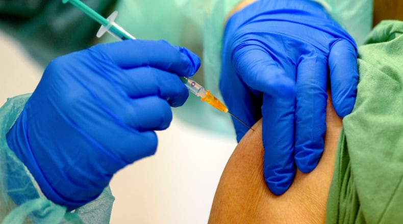 An employee of the vaccination centre of the Salzlandkreis injects a woman with a vaccination dose against the Corona virus in Stassfurt, Germany, Monday, Jan. 11, 2021. Parallel to the tightened Corona rules, vaccination has been intensified in the fight against the pandemic in the German state of Saxony-Anhalt. (Klaus-Dietmar Gabbert/dpa via AP)