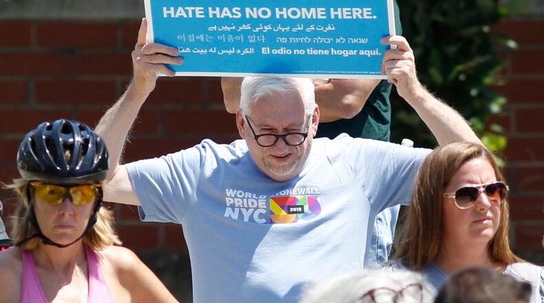 Prayer vigil attendees expressed their sadness and anger at Levitt Pavilion on Sunday afternoon after the Dayton shooting that claimed 10 lives including the shooter and injured more than two dozen others in the Oregon District at about 1 a.m. Sunday morning. Jerry Mallicoat from Miamisburg displayed this sign.  TY GREENLEES / STAFF