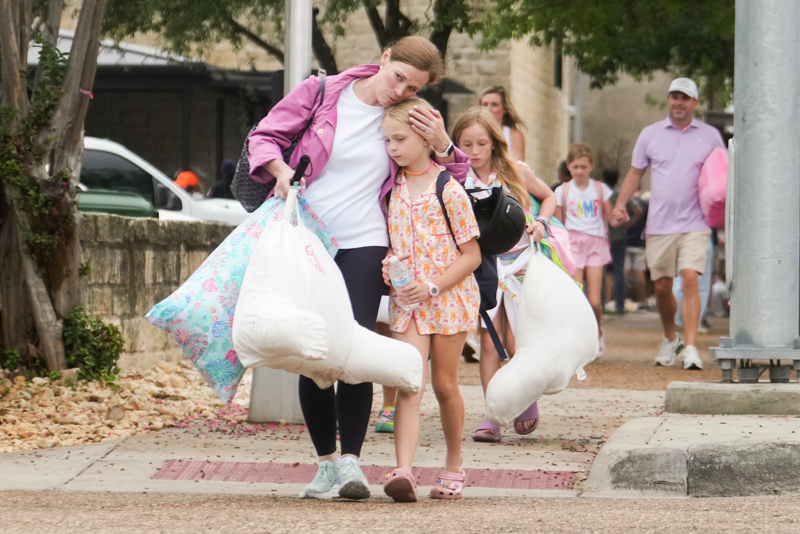 A woman and a child embrace after girls from Camp Waldemar, near the North fork of the Guadalupe River, are reunited with their families after heavy rainfall in Central Texas, Saturday, July 5, 2025. (Jason Fochtman/Houston Chronicle via AP)