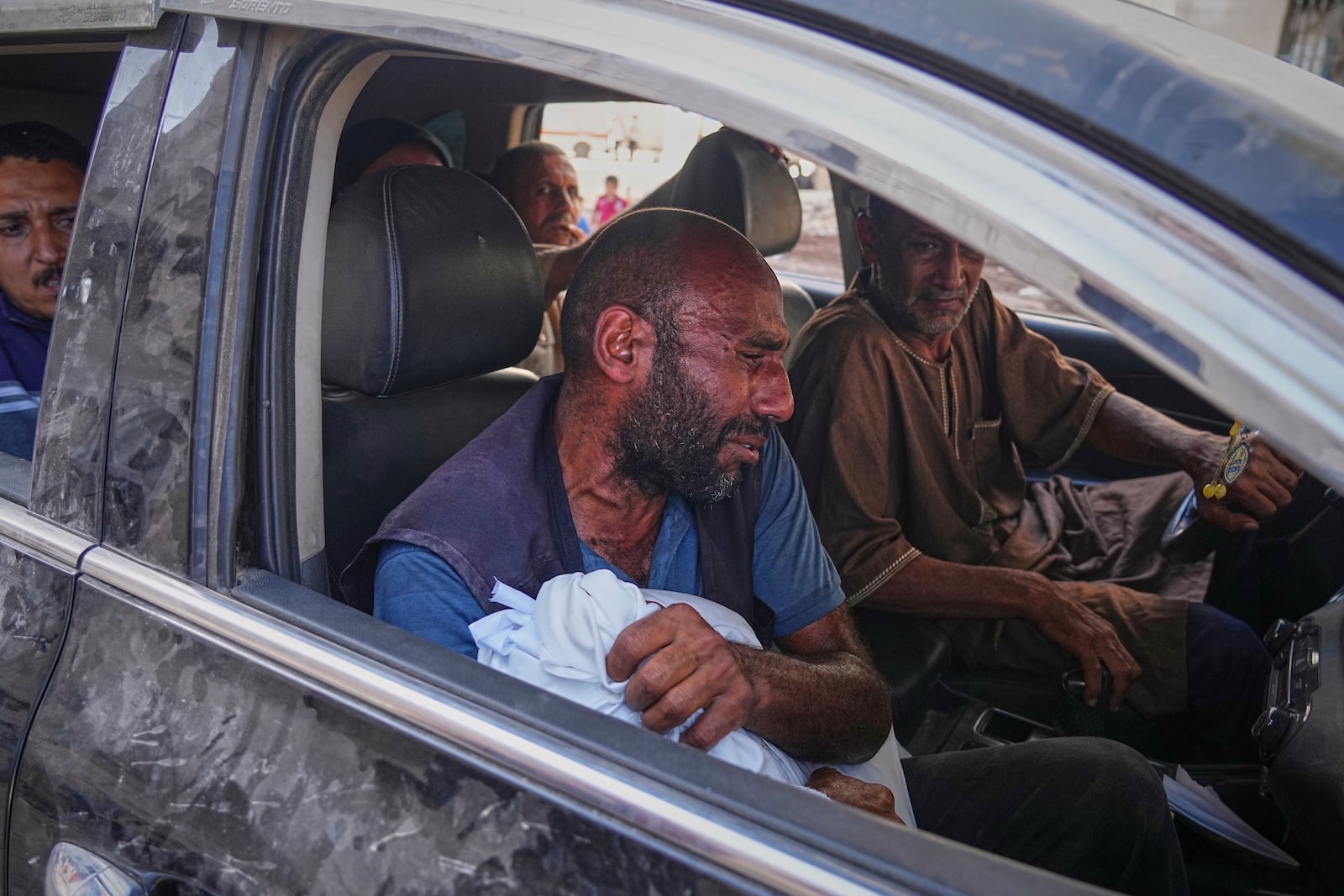 A man carries the wrapped body of a child killed in an Israeli strike that targeted a school in the northern Gaza Strip, as he arrives at Shifa Hospital. Friday, June 27, 2025, Gaza City. (AP Photo/Jehad Alshrafi)