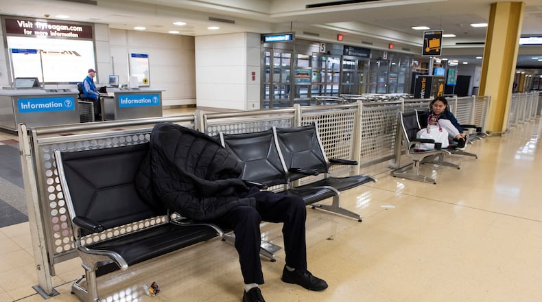 A man sleeps in the baggage claim area of Ronald Reagan National Airport, in Arlington, Va., Monday, March 16, 2026. (AP Photo/Cliff Owen)