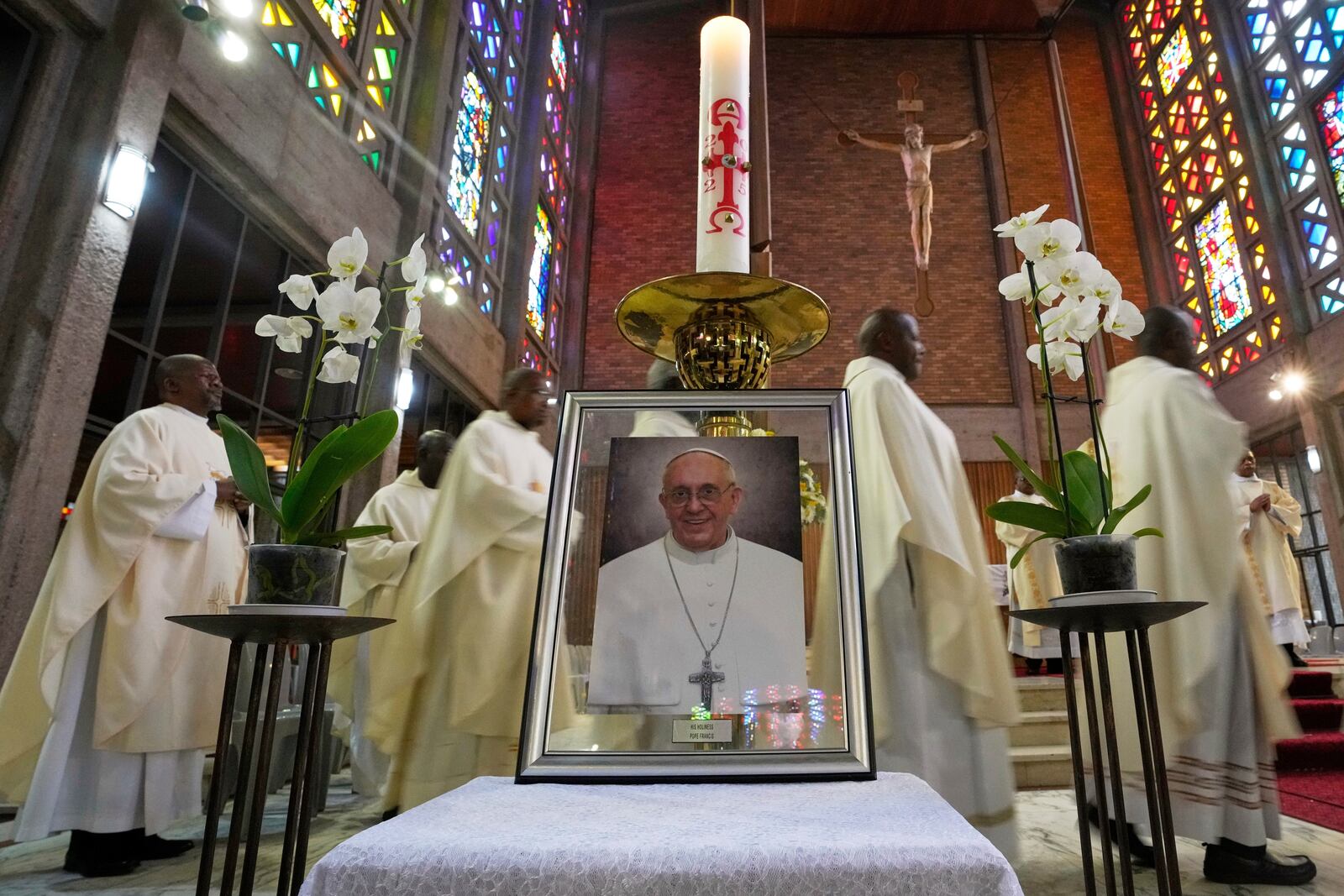 Priests walk behind a portrait of Pope Francis following a Memorial Mass, at the Cathedral of Christ the King, Johannesburg, South Africa, Wednesday, April 23, 2025. (AP Photo/Themba Hadebe)