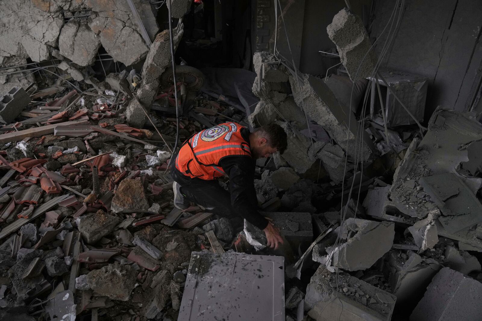 A Palestinian civil defense worker searches through the debris following an Israeli airstrike on a residential building in Gaza City, Thursday, April 24, 2025. (AP Photo/Jehad Alshrafi)
