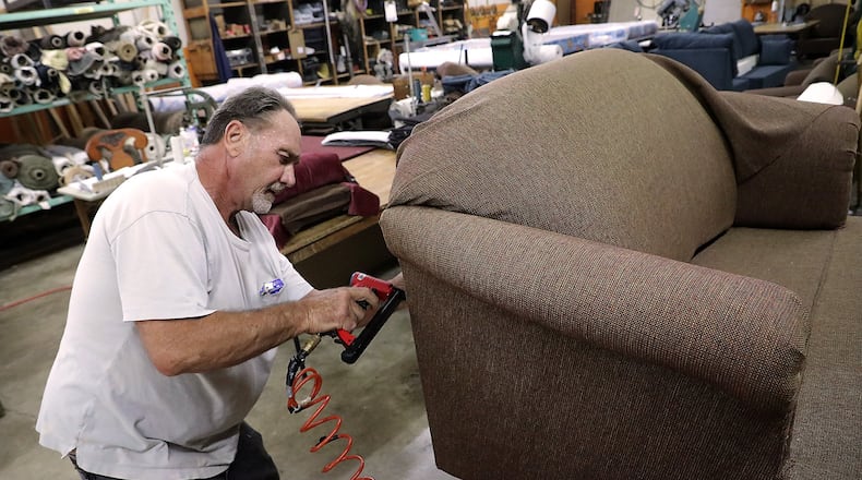 Richard Donaldson upholsters a love seat in the Jim Miller Furniture workshop Wednesday at their new location at 2960 Dayton Road. BILL LACKEY/STAFF