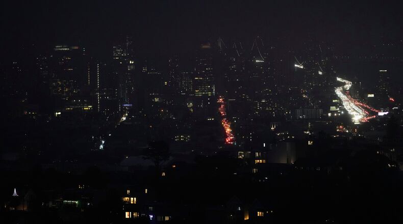 Fog and power outages darken the skyline as traffic moves in San Francisco, Saturday, Dec. 20, 2025. (AP Photo/Jeff Chiu)