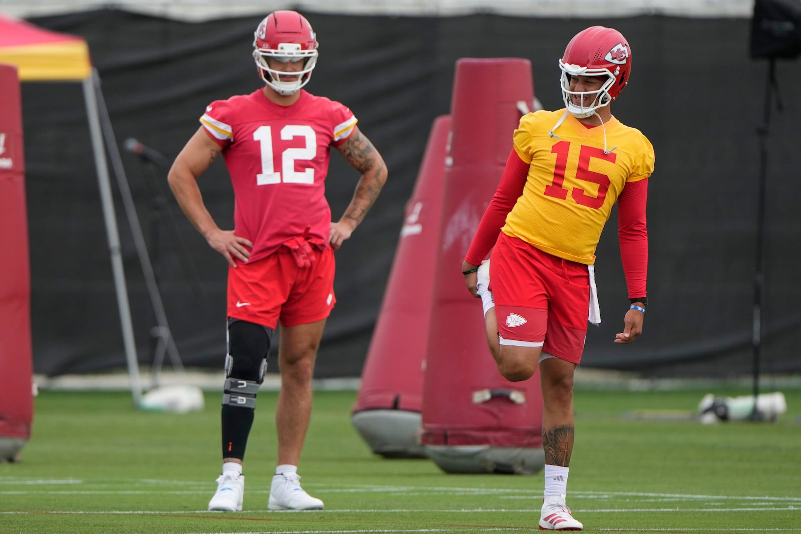 Kansas City Chiefs quarterback Patrick Mahomes (15) and tight end Jared Wiley (12) stretch during the NFL football team's practice Tuesday, June 17, 2025, in Kansas City, Mo. (AP Photo/Charlie Riedel)