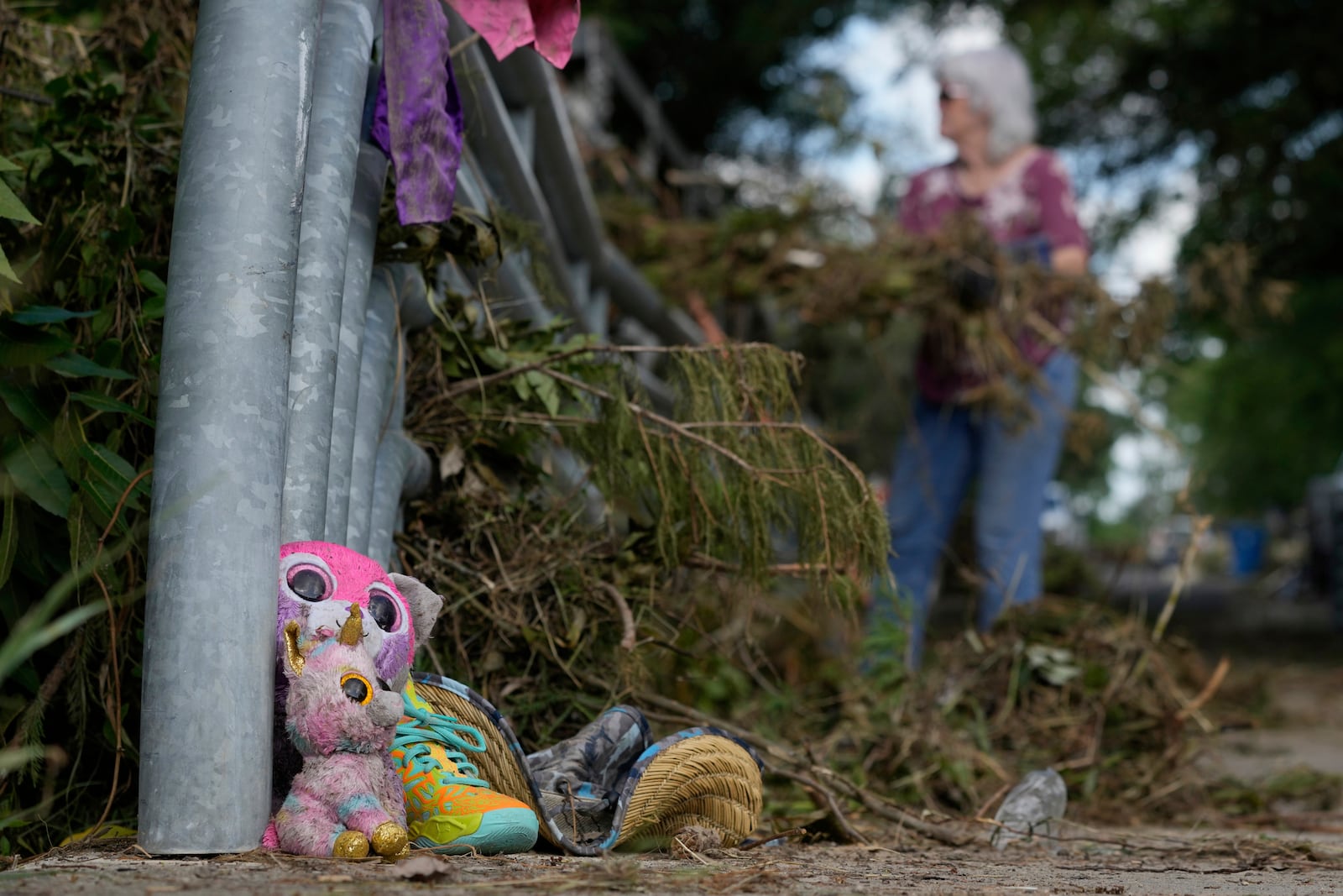 Lost items sit at a bridge as a volunteer cleans up debris on Tuesday, July 8, 2025, after a flash flood swept through the area in Kerrville, Texas. (AP Photo/Ashley Landis)