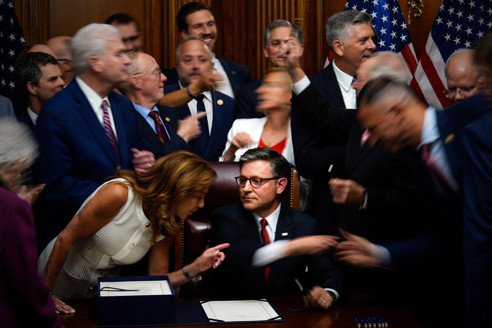 Republican members of Congress reach to shake hands with Speaker of the House Mike Johnson, R-La., center bottom, after Johnson signed President Donald Trump's signature bill of tax breaks and spending cuts, Thursday, July 3, 2025, at the Capitol in Washington. (AP Photo/Julia Demaree Nikhinson)